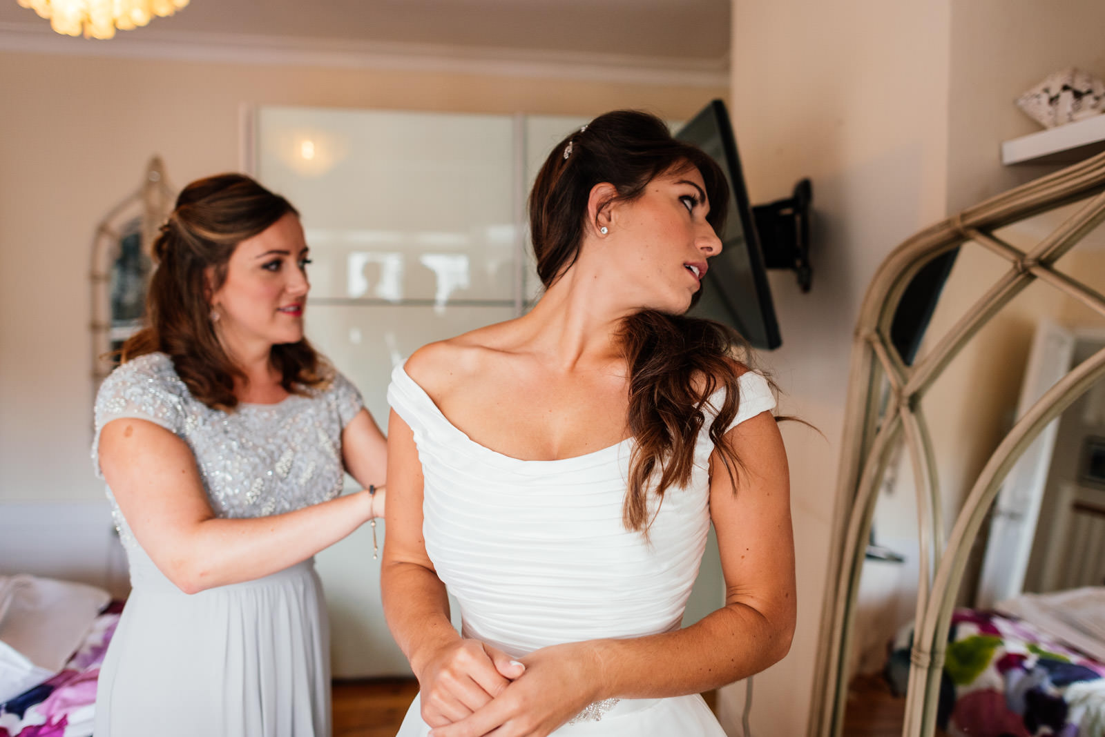 bride and bridesmaids helping get the dress on