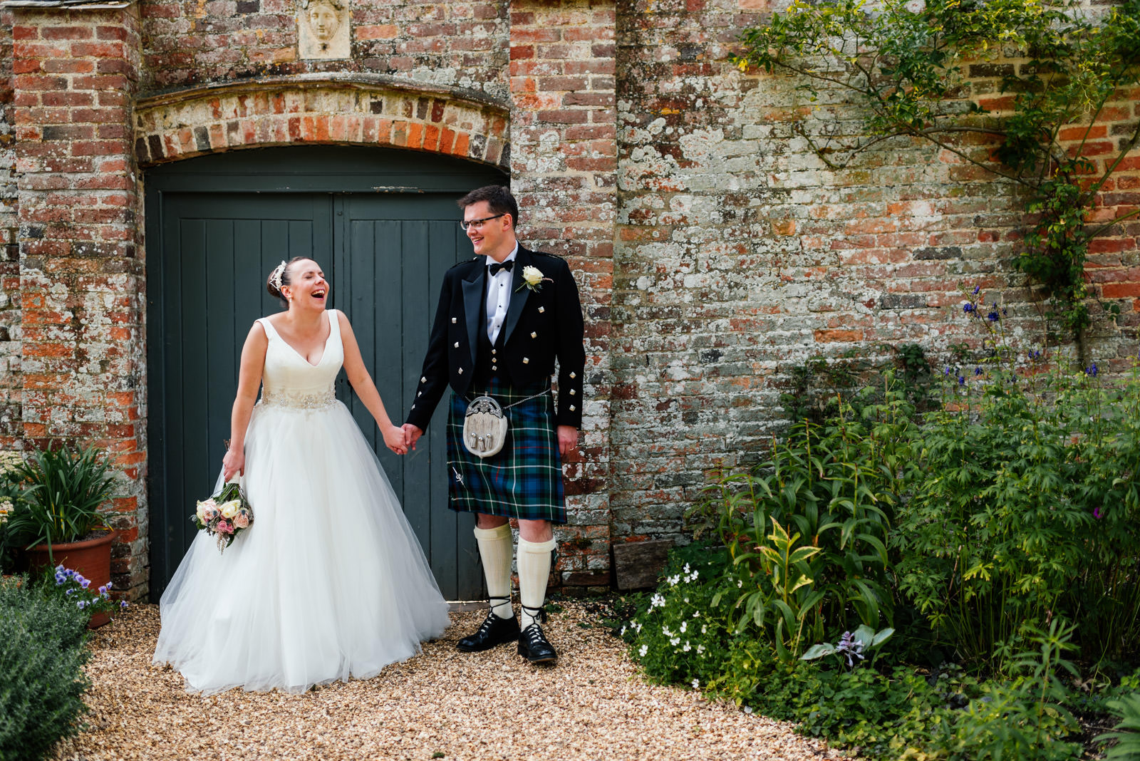 bride and groom in front of garden fence