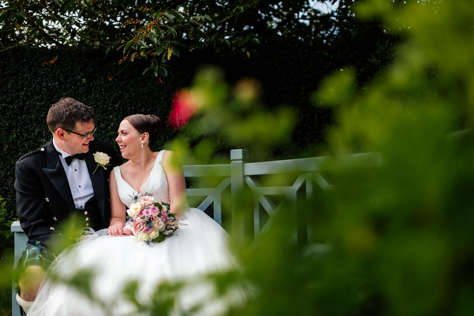 bride and groom portrait sitting down on bench in the garden