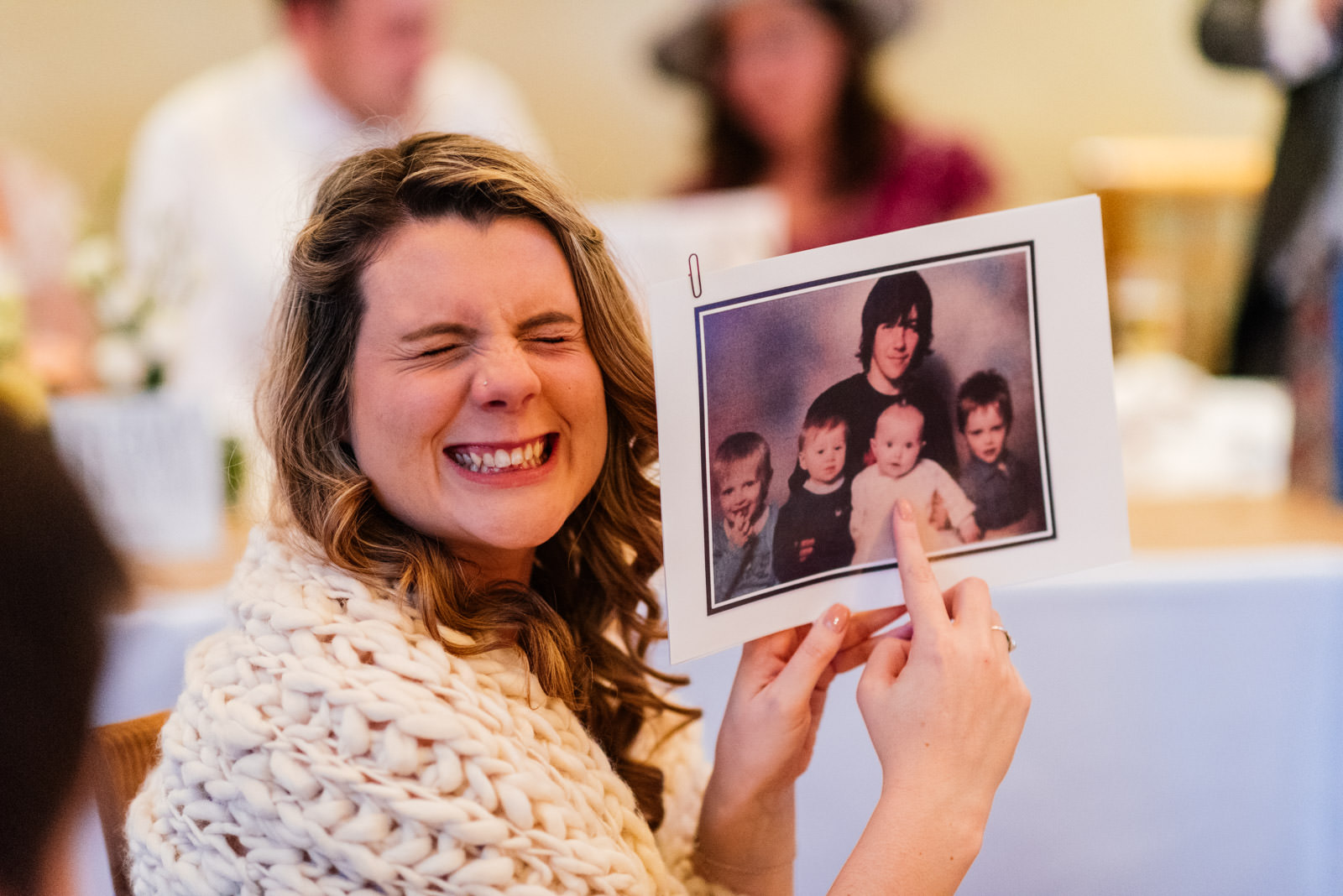 bridesmaid smiling whilst showing a photo of the groom as a child