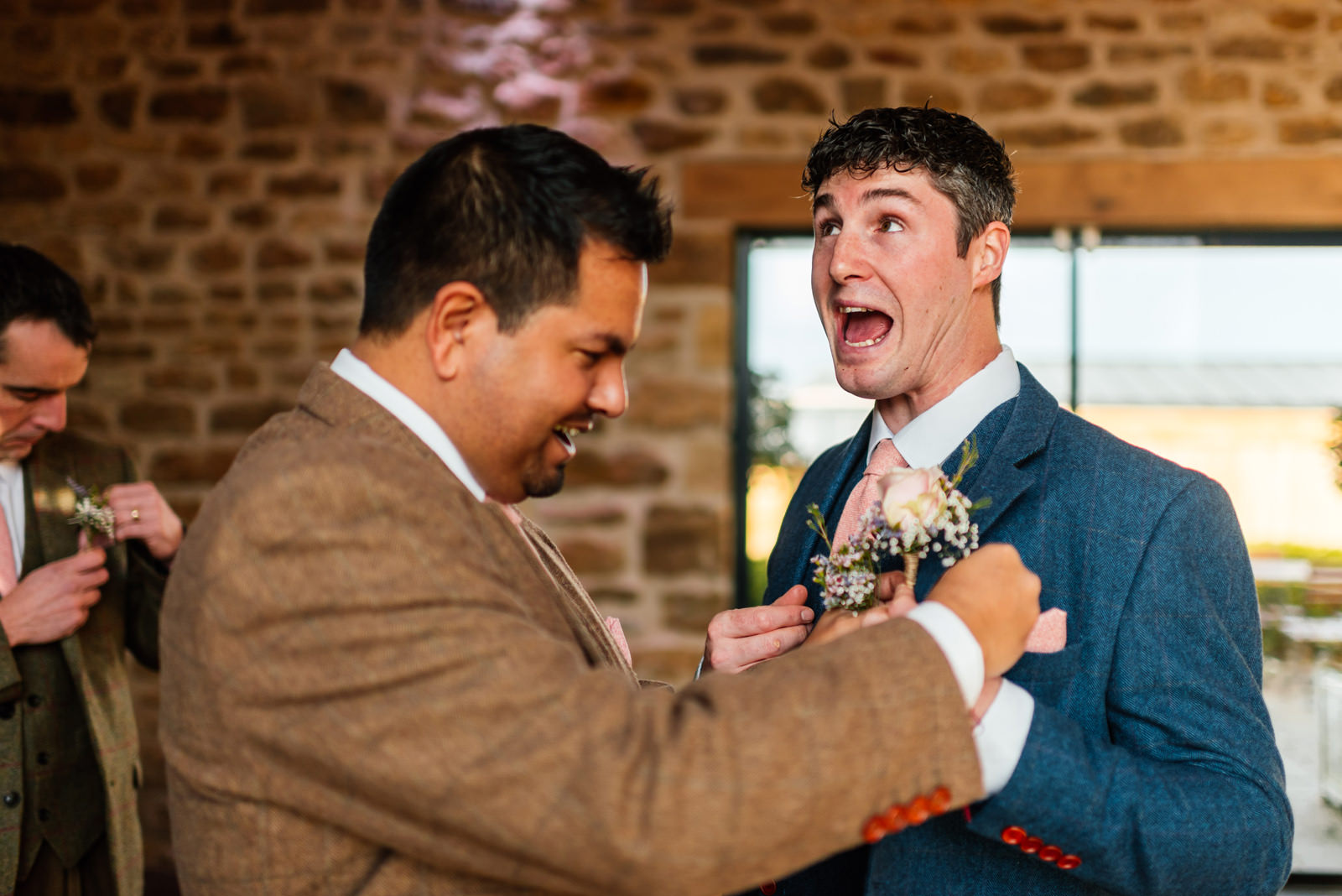 groom messing around when putting on his button hole
