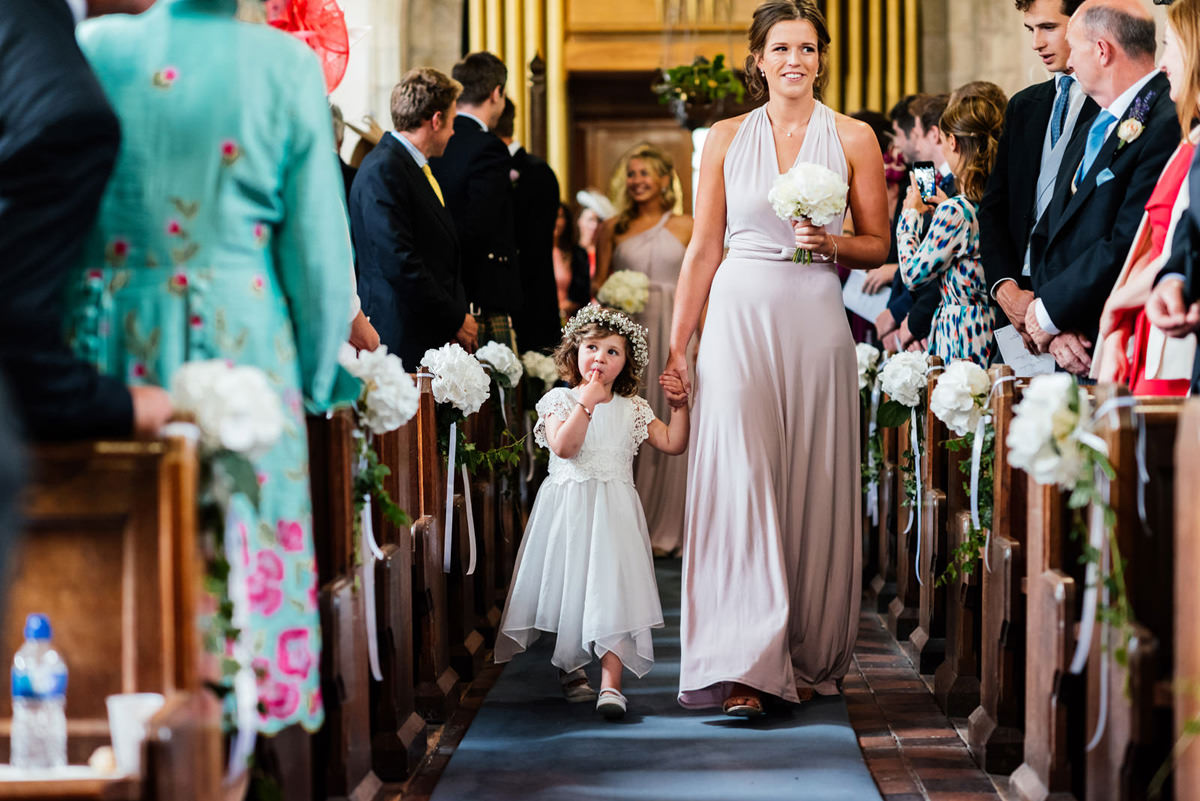 flower girl with flower crown walking down aisle