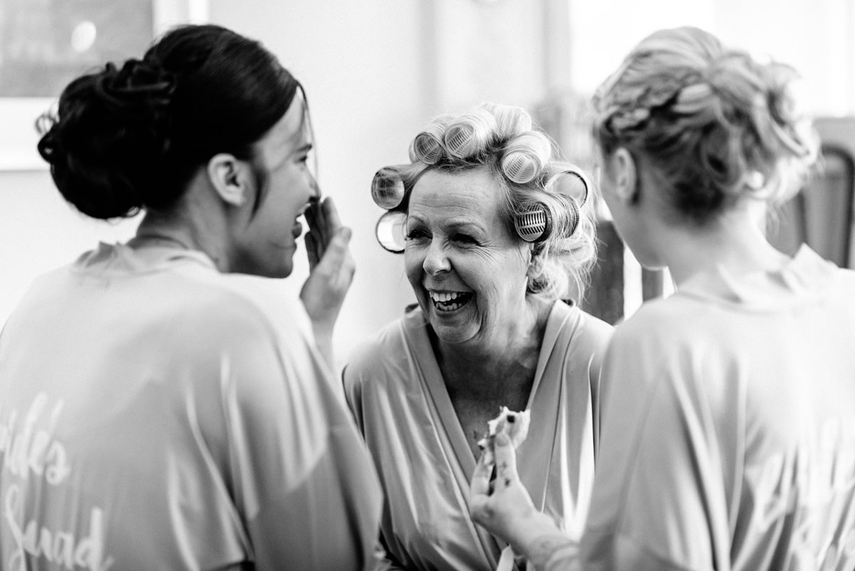Bride's mum and bridesmaids laughing during morning prep