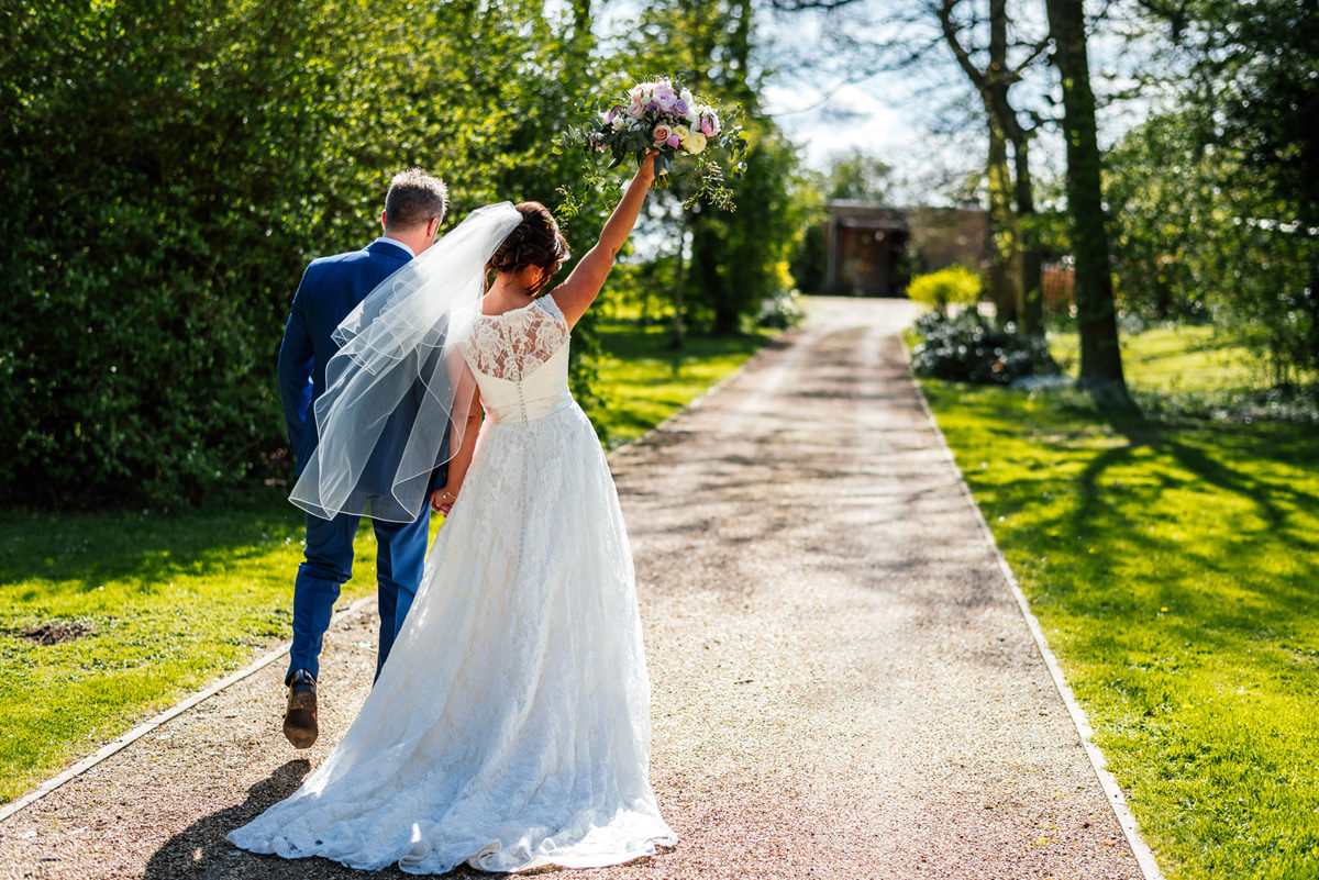 bride and groom walking away with bouquet high in the air