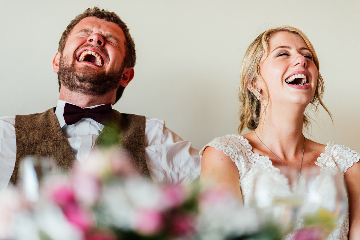 bride and groom laughing during wedding speeches