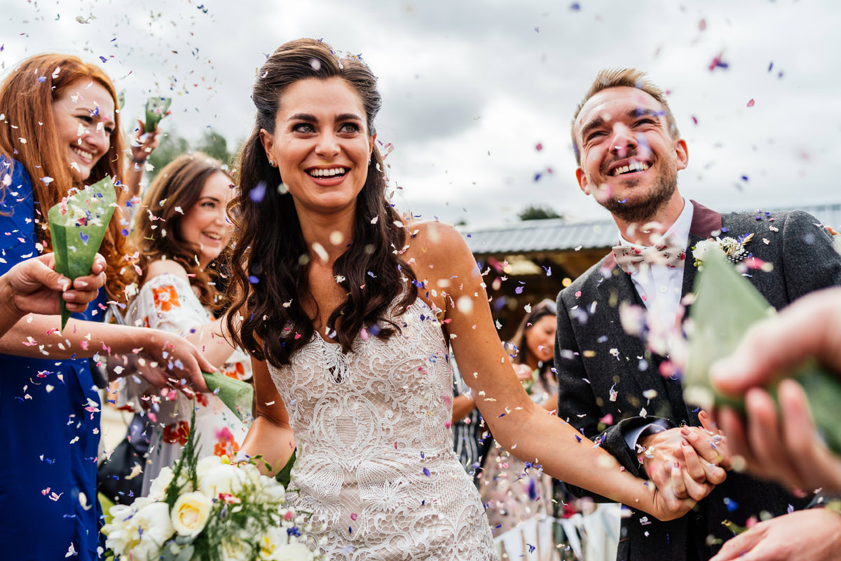 bride and groom get showered with confetti