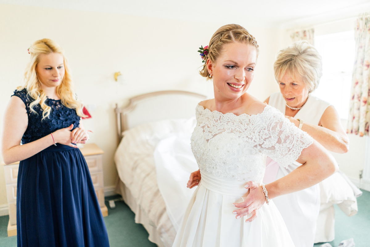 mother of the bride helping her daughter get into her wedding dress