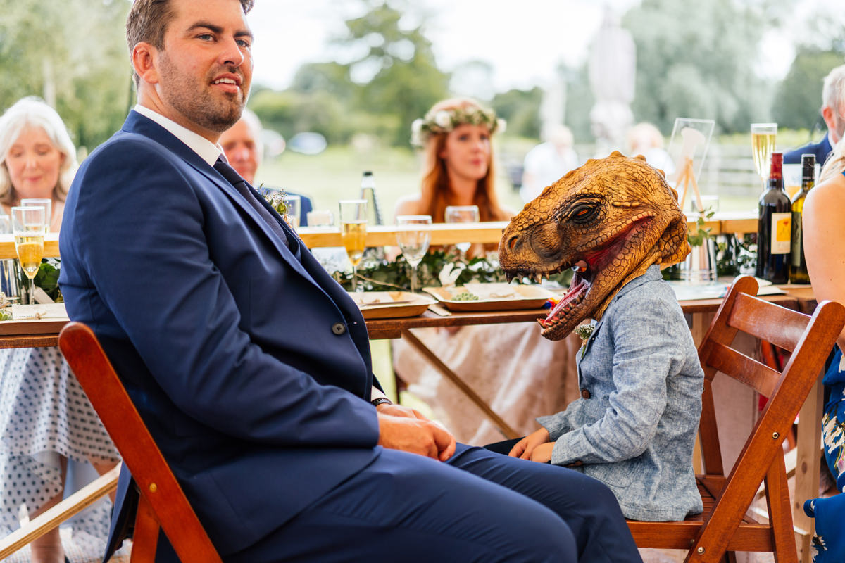 boy at wedding wearing dinosaur head