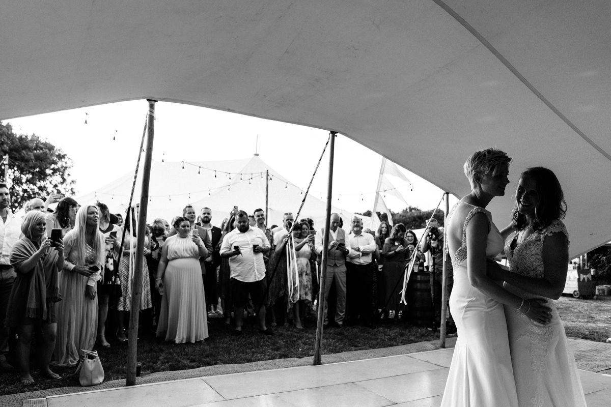 Two brides have their first dance in a tent