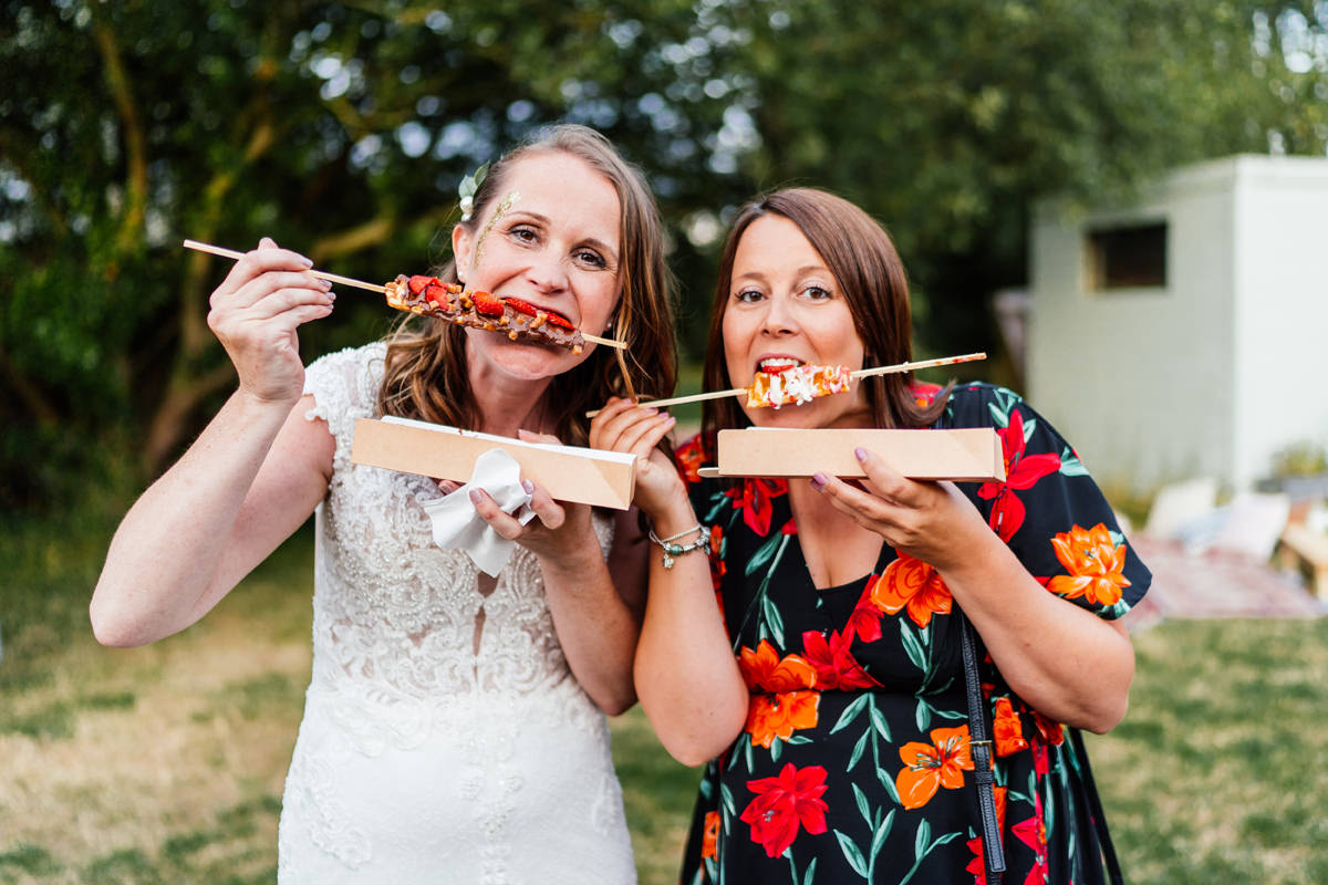 Bride and friend eating waffle stick