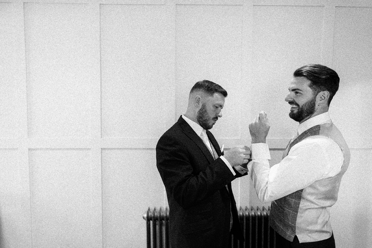 Best man helps the groom with his cufflinks