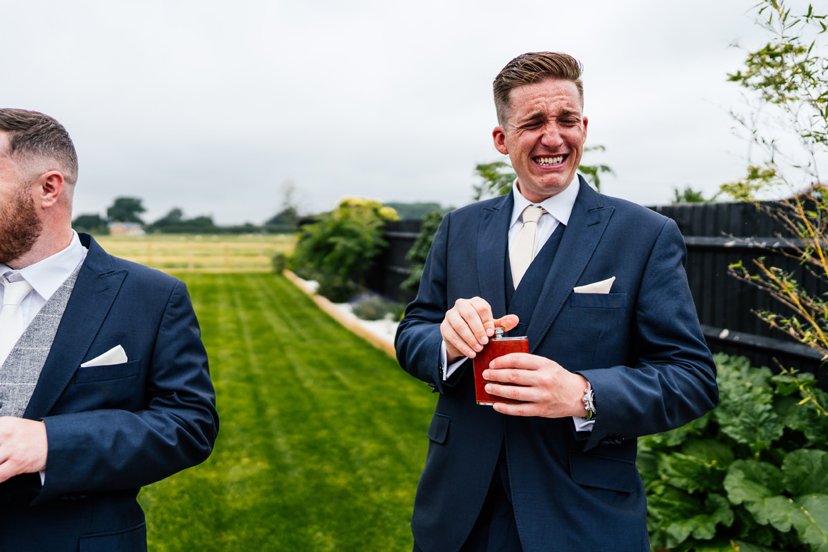 Groomsman pulling a face after taking a shot of whiskey