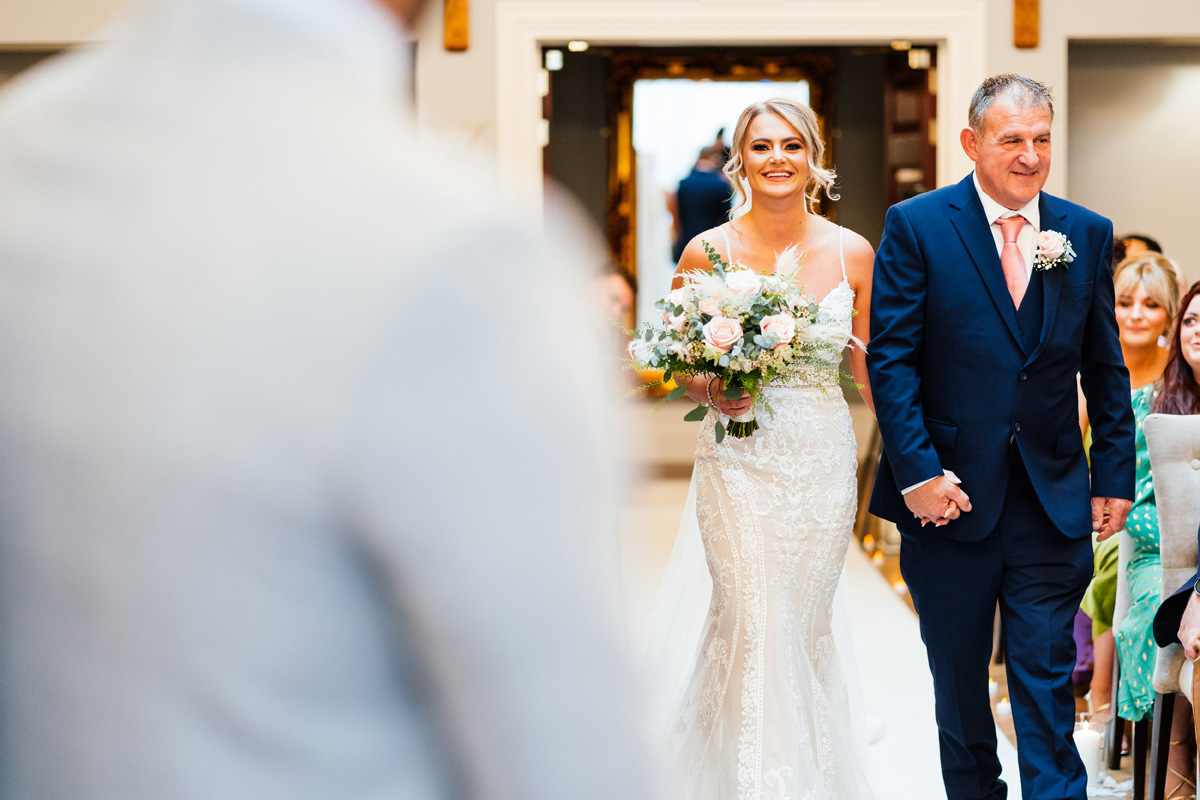 father of the bride walks his daughter down the aisle at the beginning of the marriage ceremony