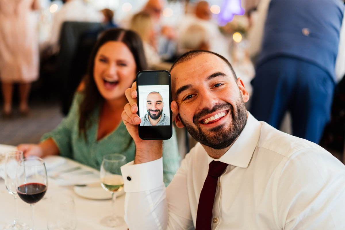 wedding guest holding his phone up to show a photo of himself