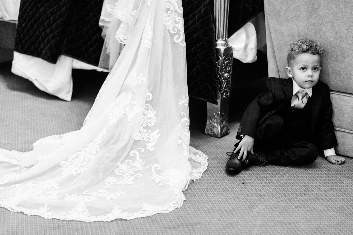 page boy waiting on the floor next to the wedding dress hanging up