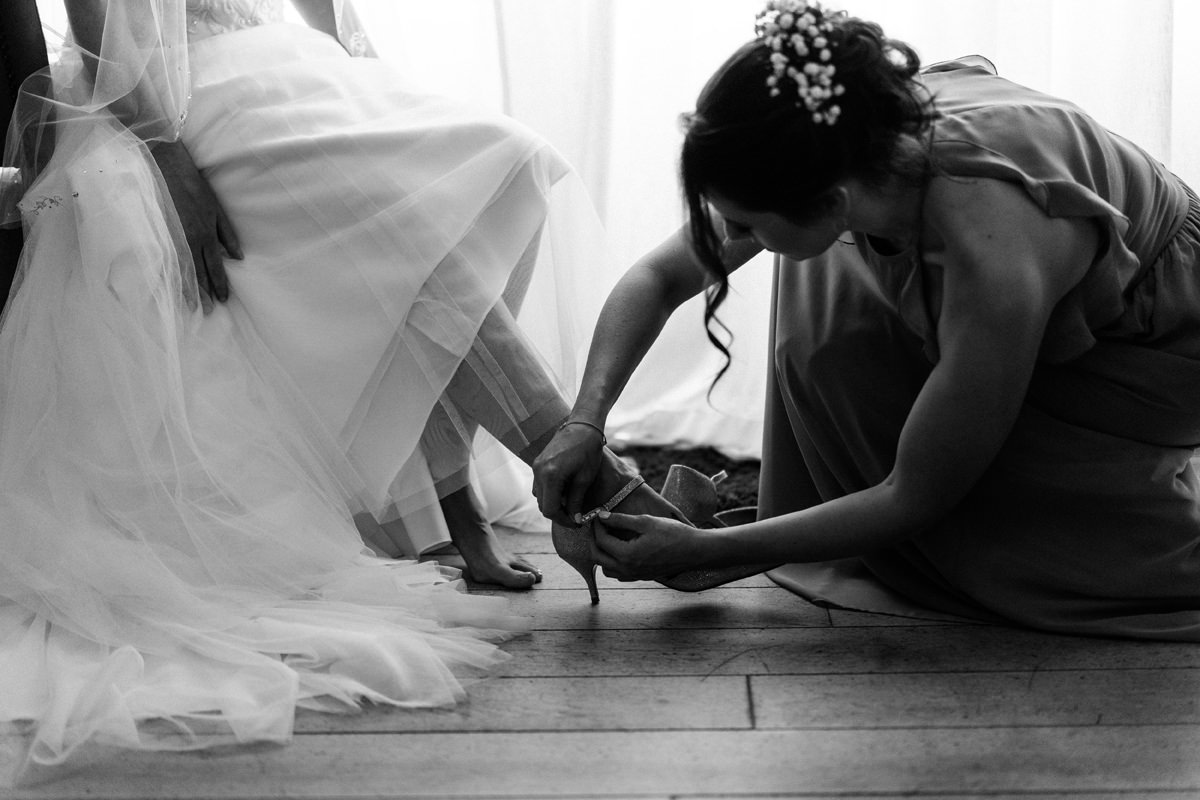 bride helping to put bride's shoes on