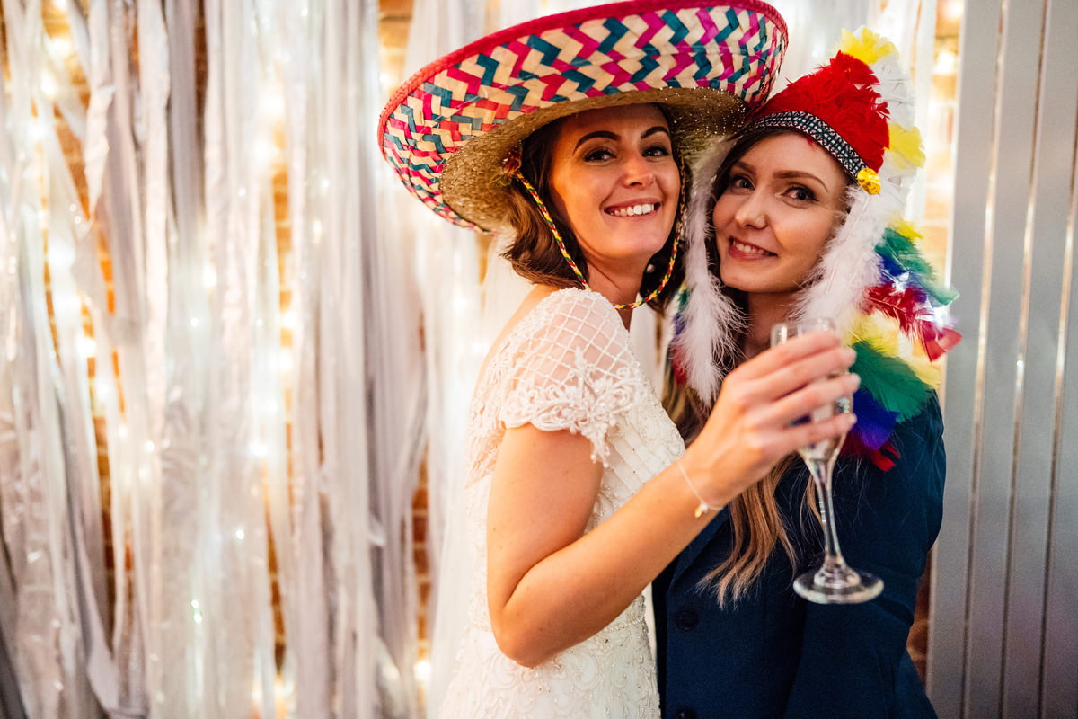 bride and her friend wear silly hats for the photo booth