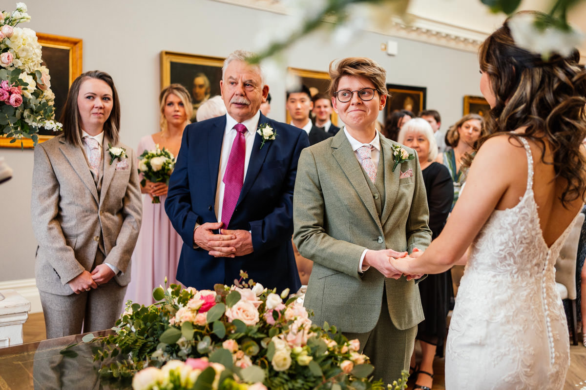 brides exchange vows with wedding guests looking on