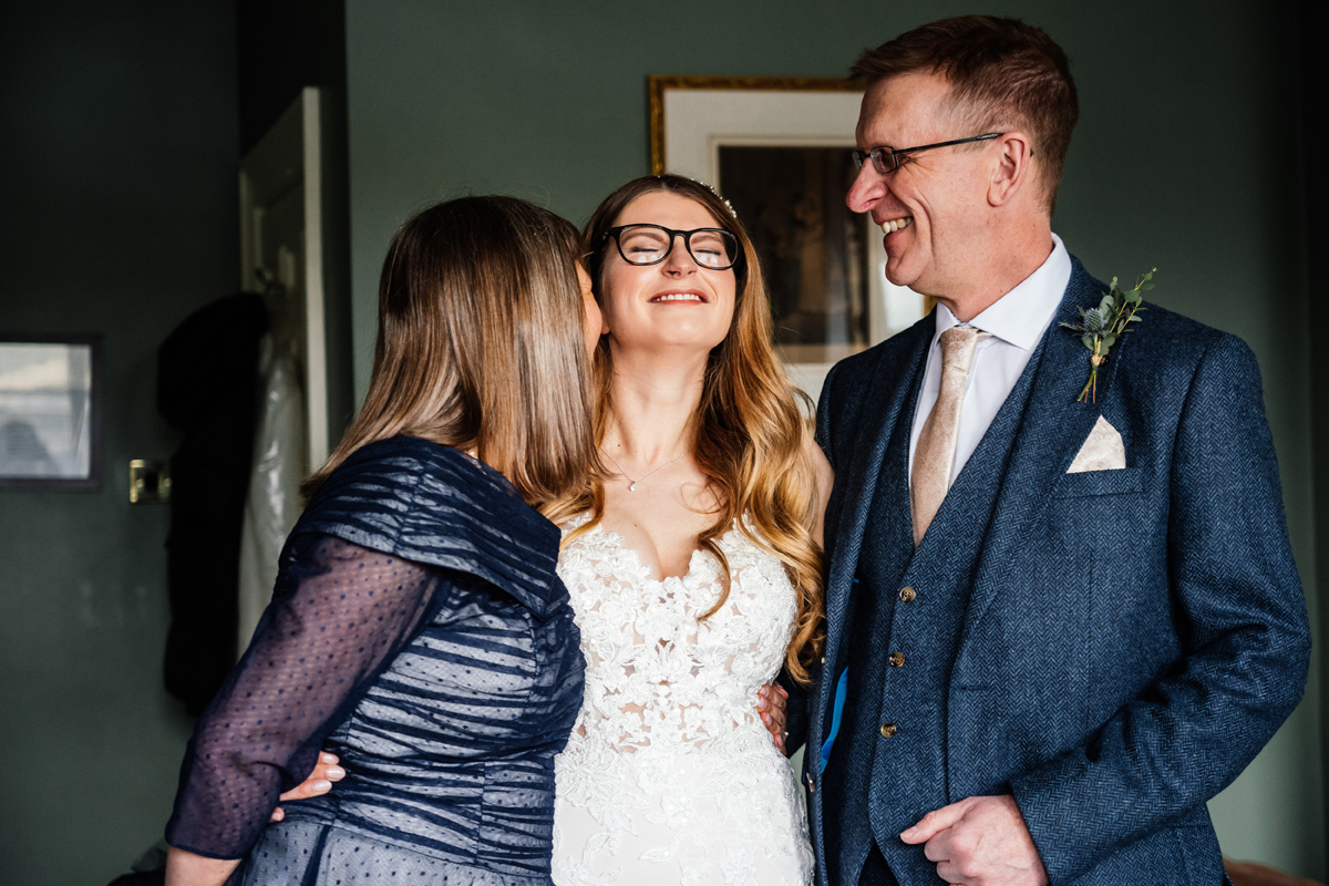 bride with her mum and dad in her wedding dress just before the marriage ceremony