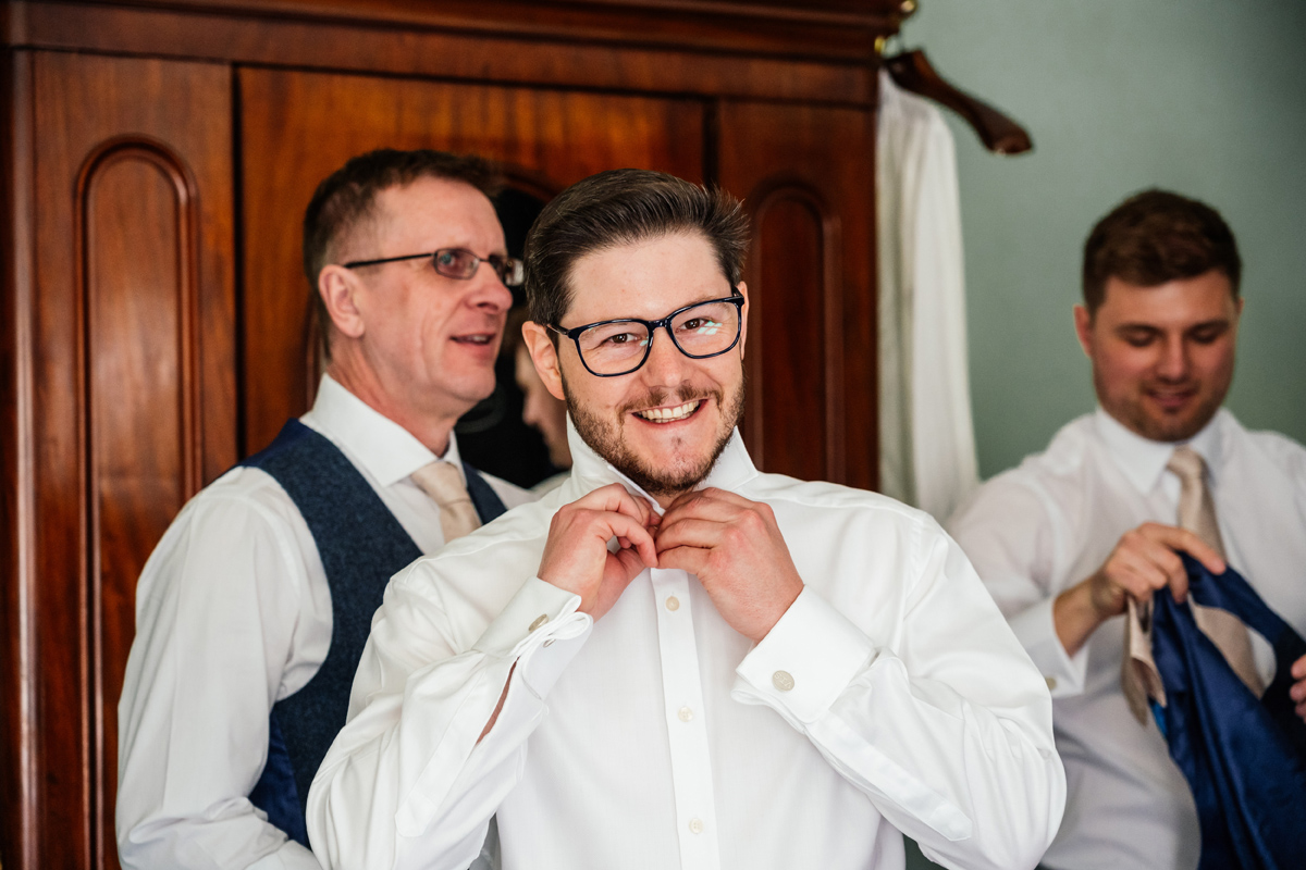 Groom getting dressed with his groomsmen on the morning of his wedding.