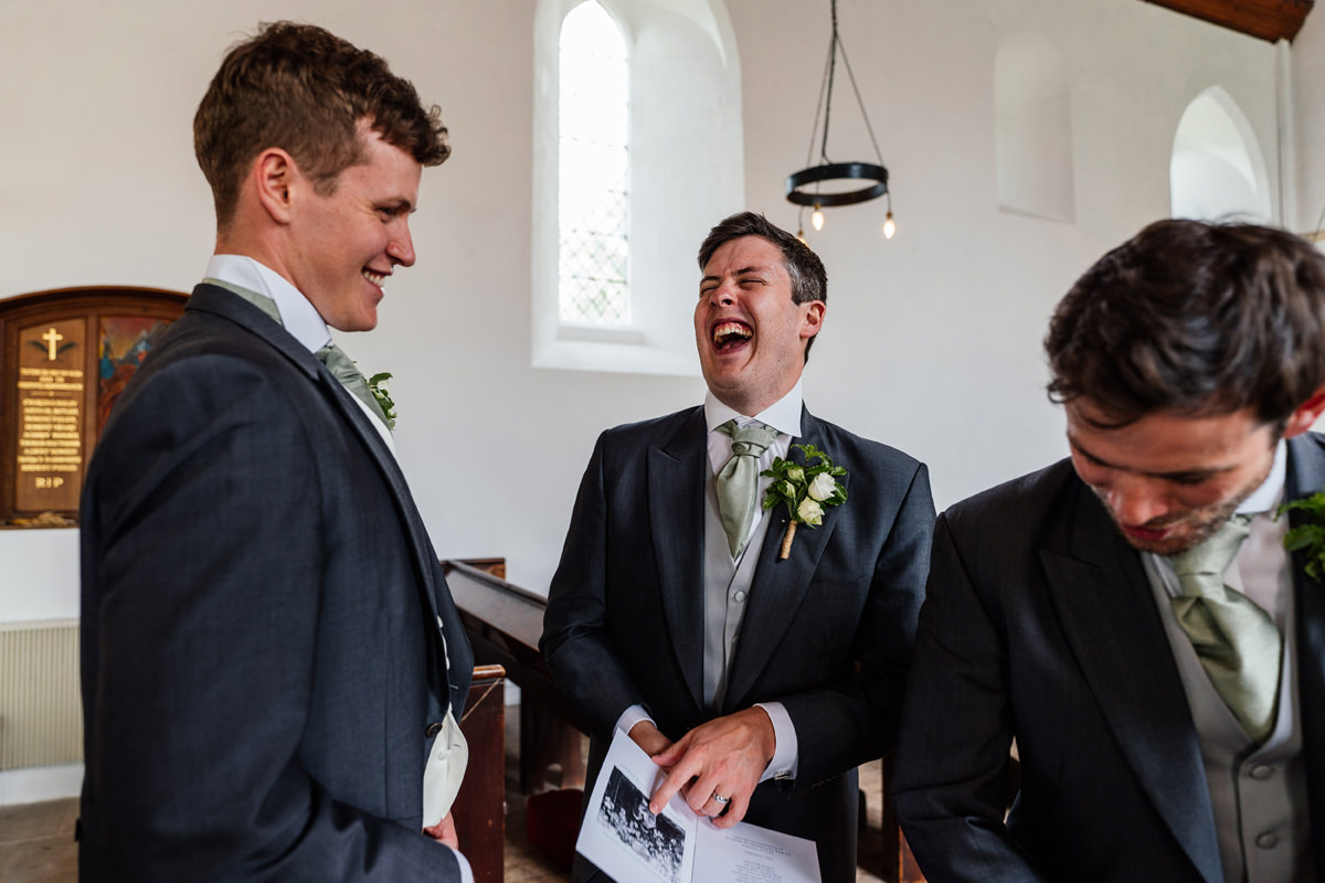 groomsman laughing in the church as they get everything ready for the ceremony