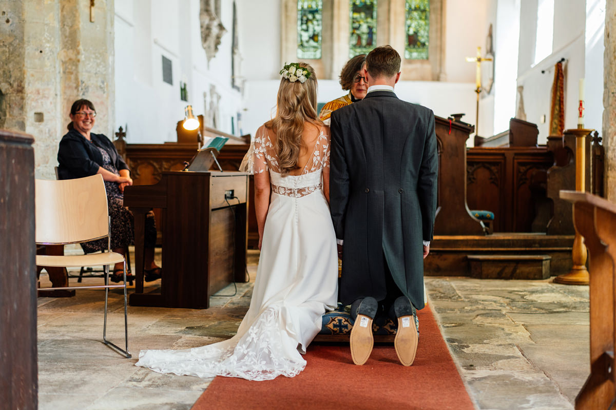 bride and groom kneeling on church during the marriage ceremony