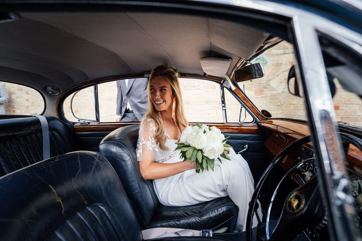 bride sitting in the jaguar waiting to be driven to the drinks reception
