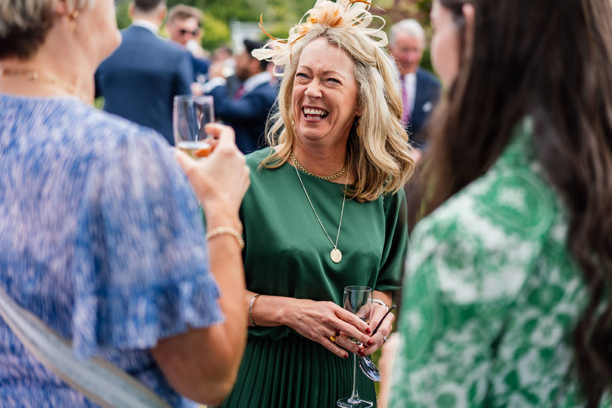 wedding guest smiling and laughing as she enjoys chatting with family and friends