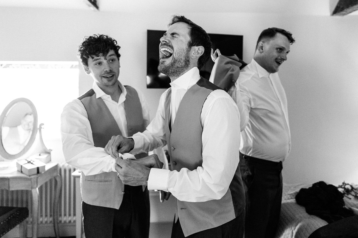 Groomsman laughing as he gets ready in the morning
