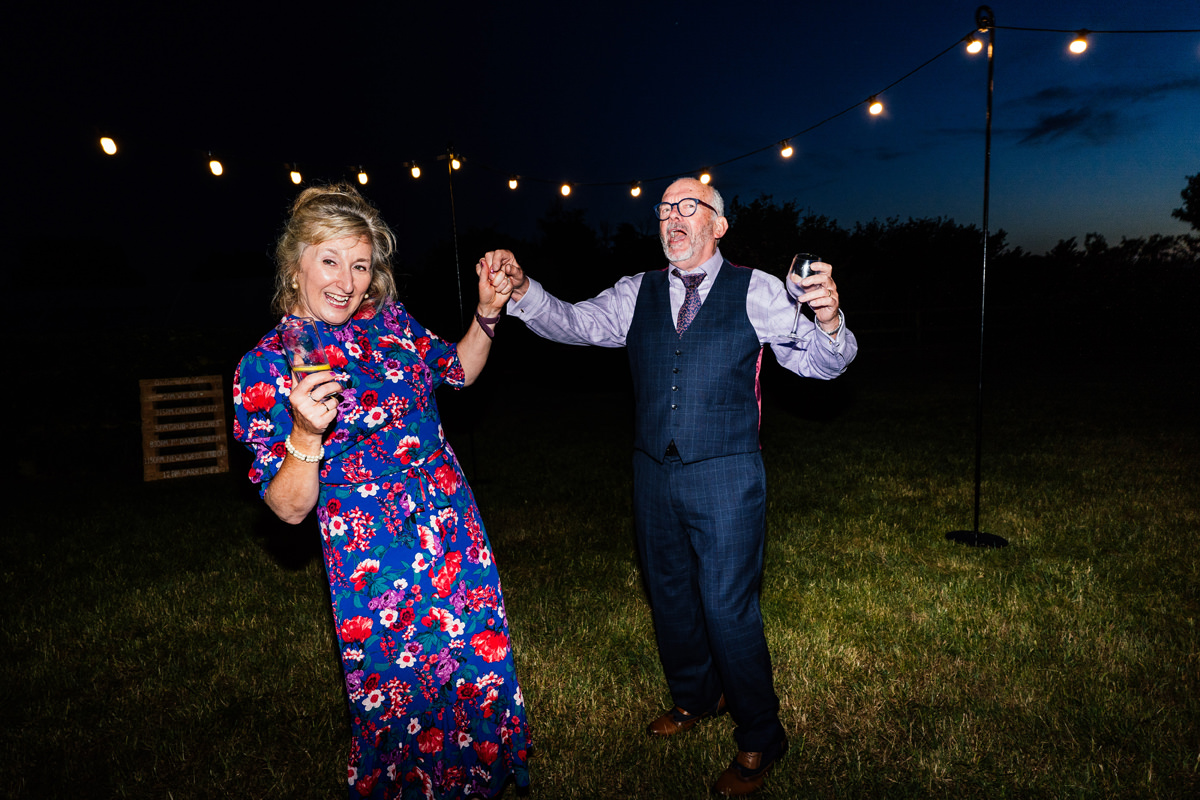 two wedding guests dancing outside of the marquee in the dark