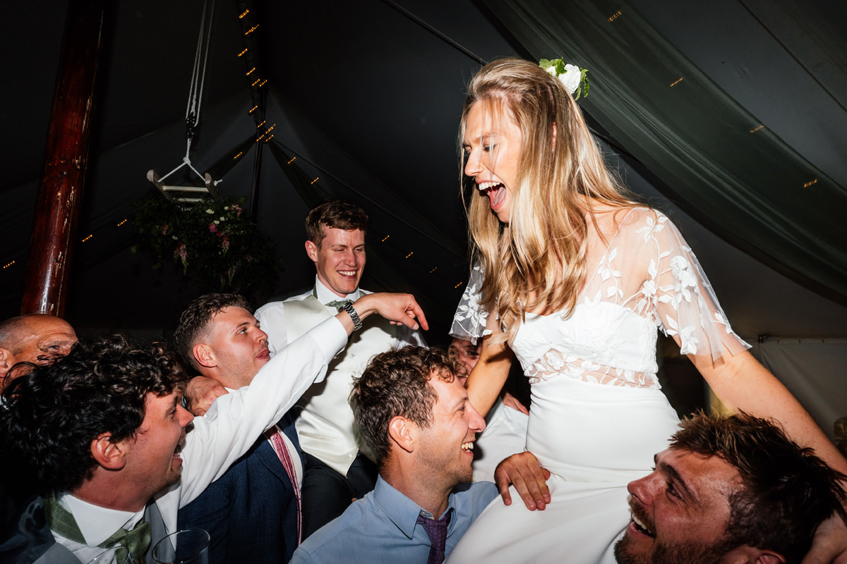 bride and groom being lifted up on to shoulders during the dancing on the dance floor