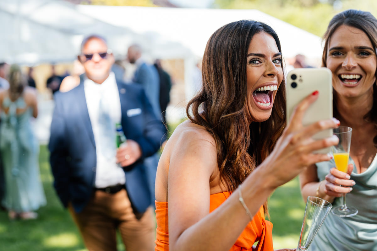 Wedding guest laughing whilst taking a selfie