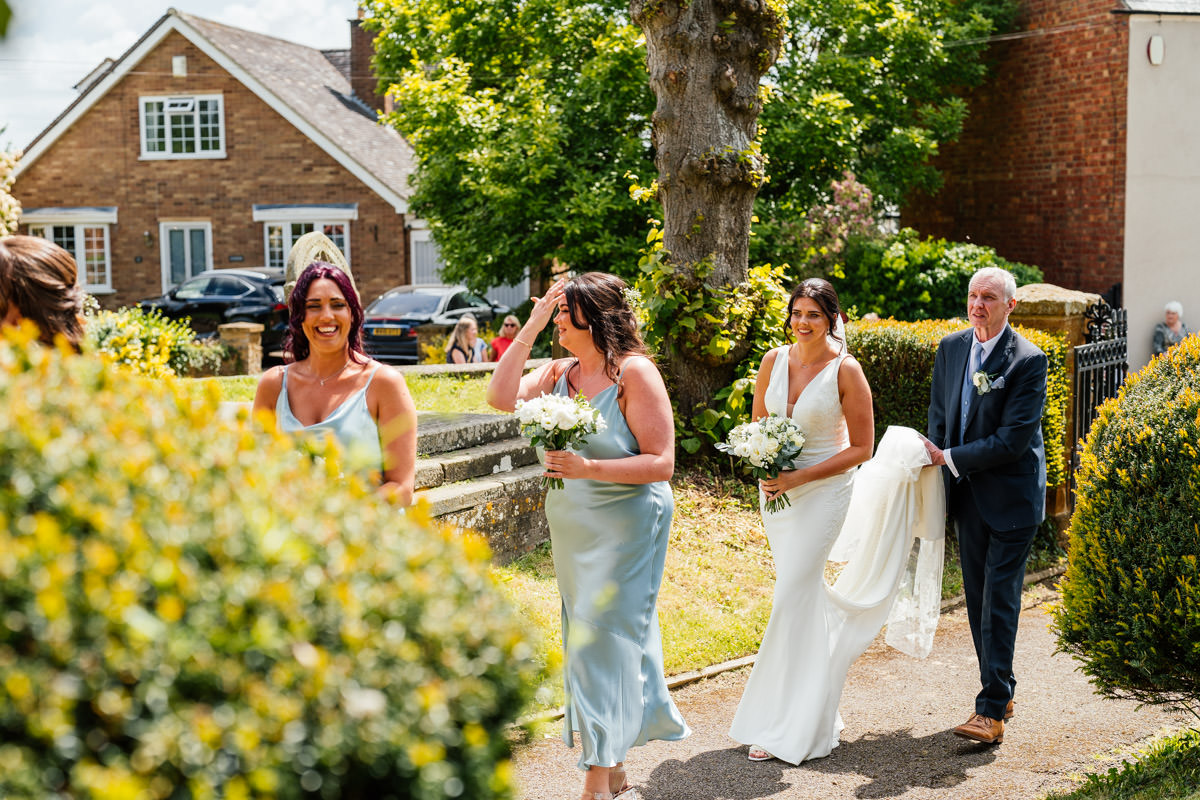 Bride, bridesmaids and father of the bride walking to the church