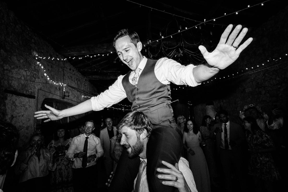 Groom being held up on the shoulders of his friend during the dancing