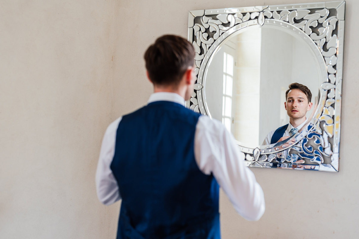Groom adjusting his tie in the mirror