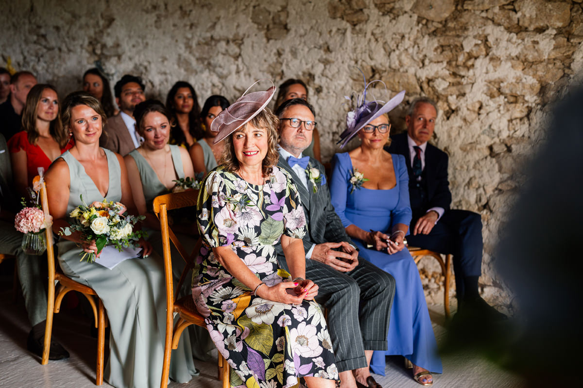 Family and friends looking on during the wedding ceremony in the barn at Chateau Soulac