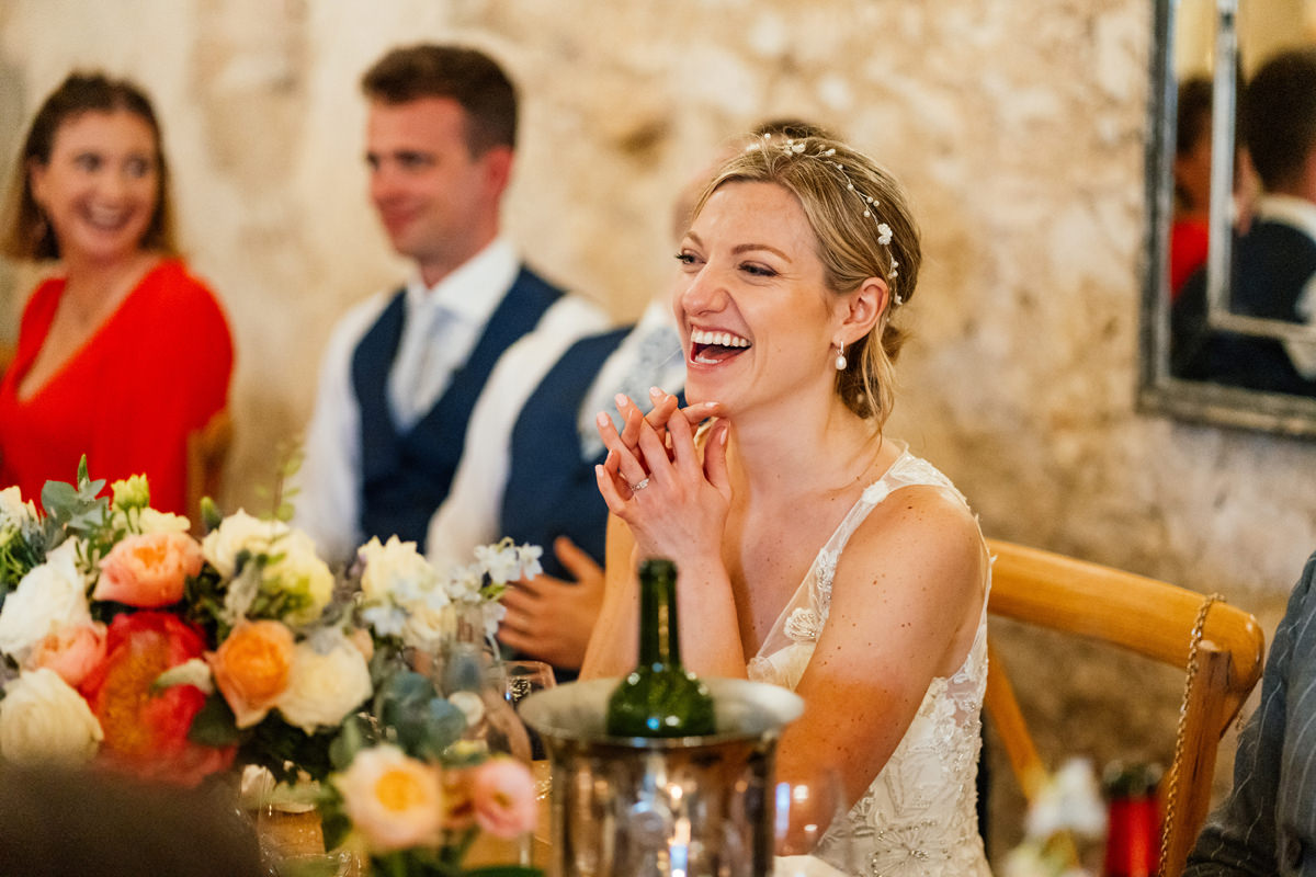 Bride laughing as she listens to the speeches