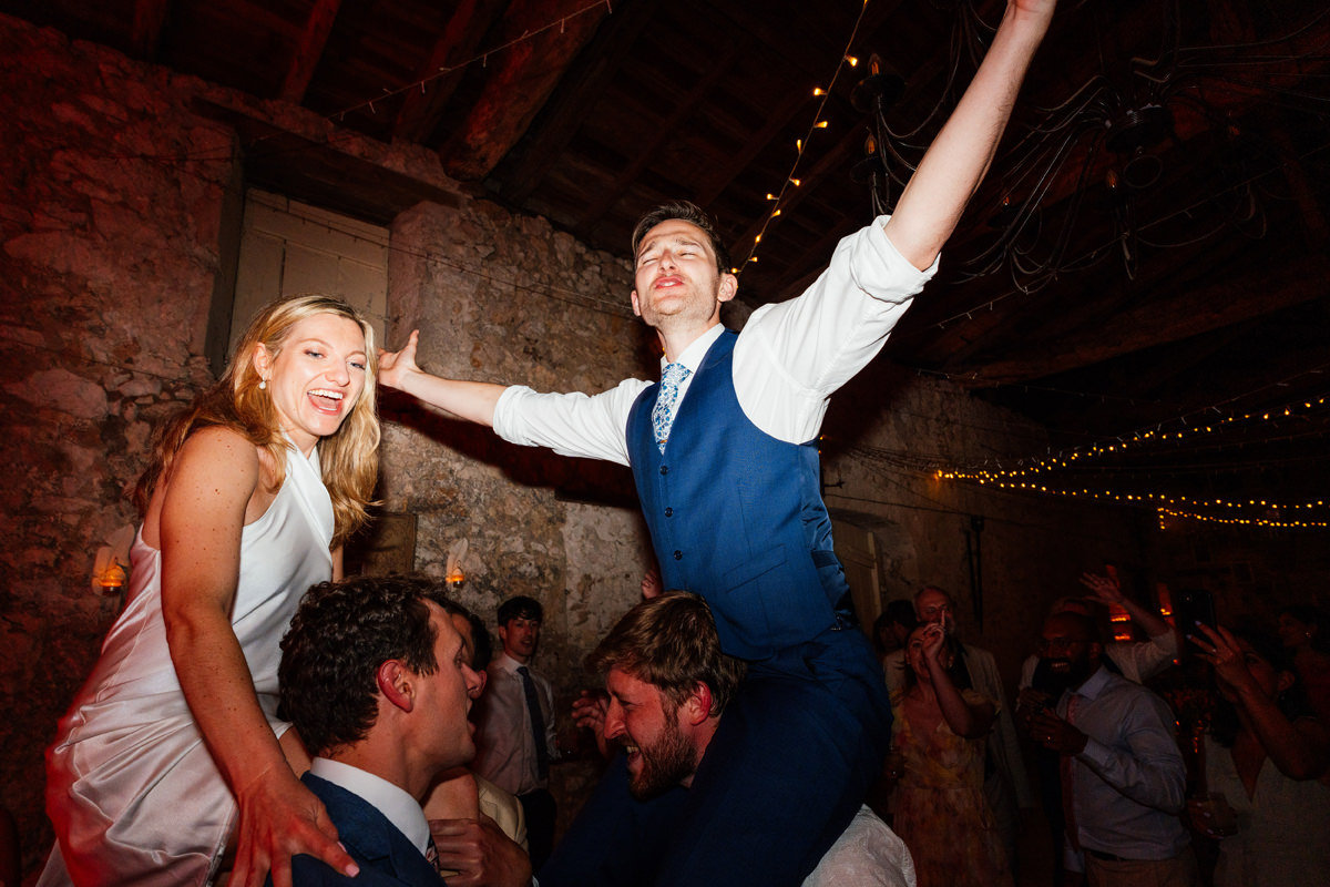 Bride and groom on the shoulders of friends on the dance floor